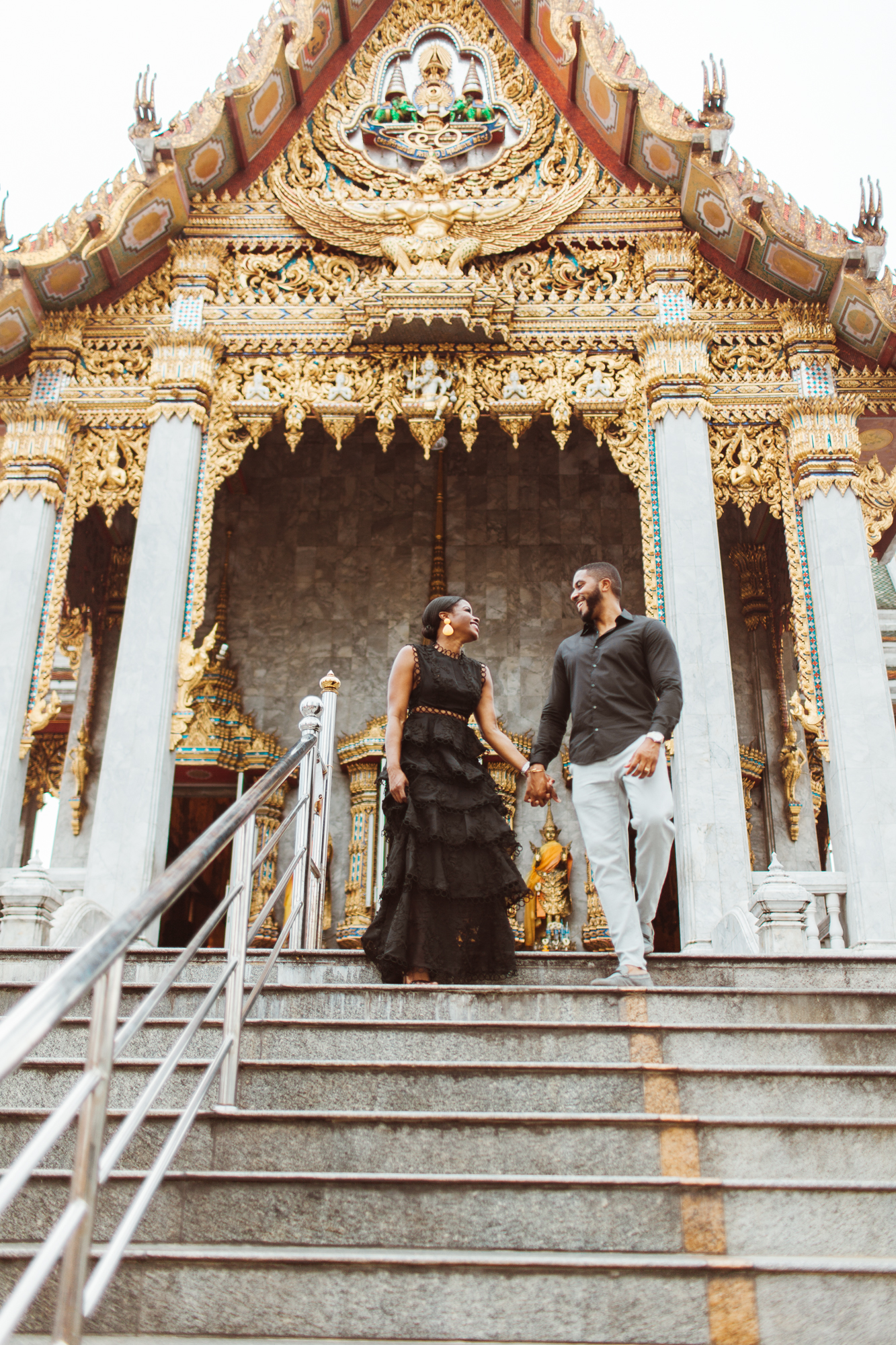 African American couple walking down some stairs in a local Thai temple.