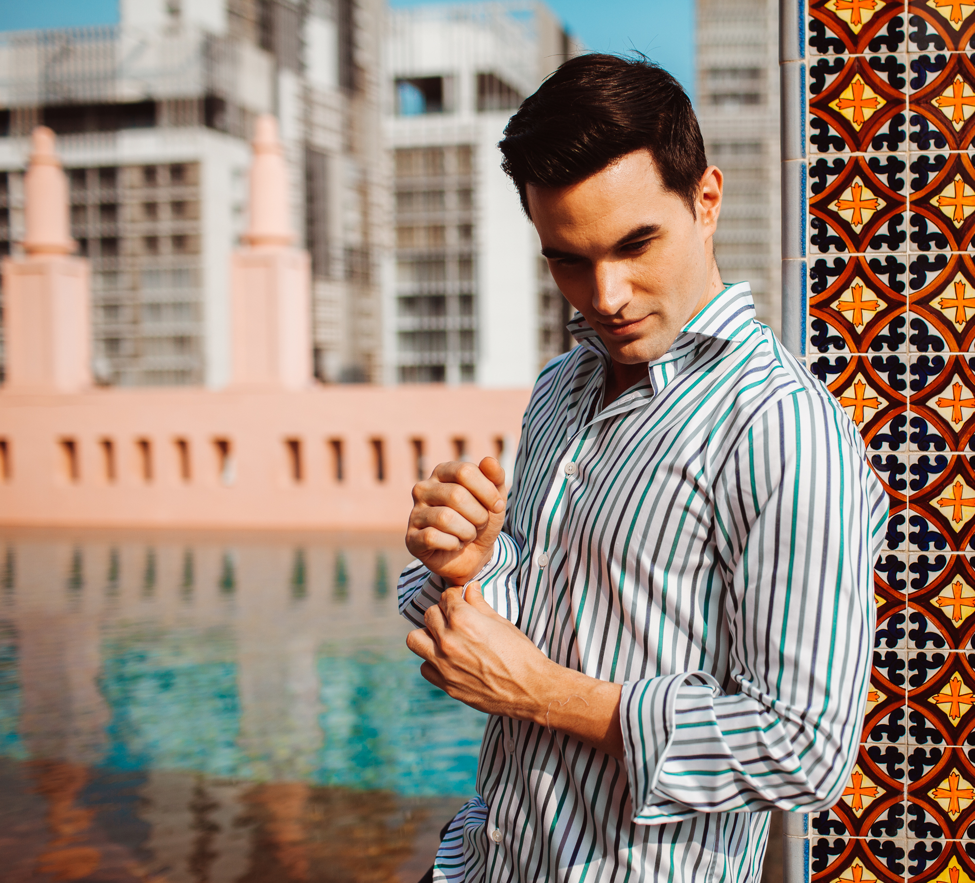 Male model by the pool wearing striped dress shirt